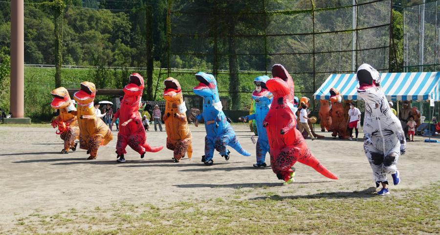 恐竜の着ぐるみを着て走るレースの様子の写真