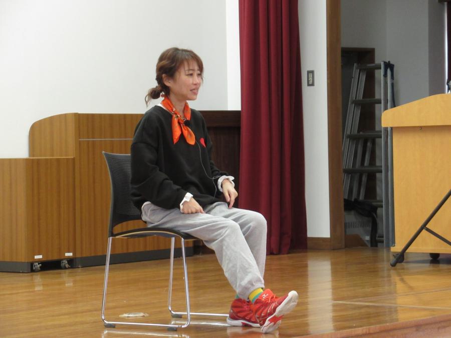 講師の清水さんが椅子に座り足を伸ばす運動を指導している様子