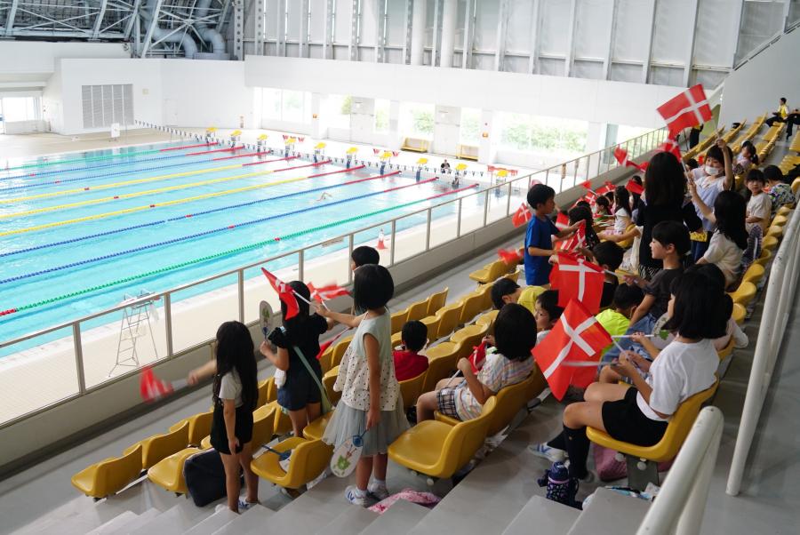 児童たちが、デンマーク水泳連盟競泳ナショナルチームを応援している様子の写真