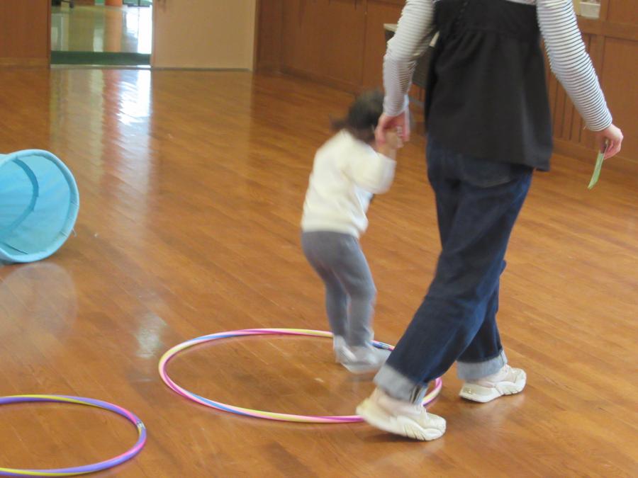 手を繋いでフラフープを飛んでいる親子の写真