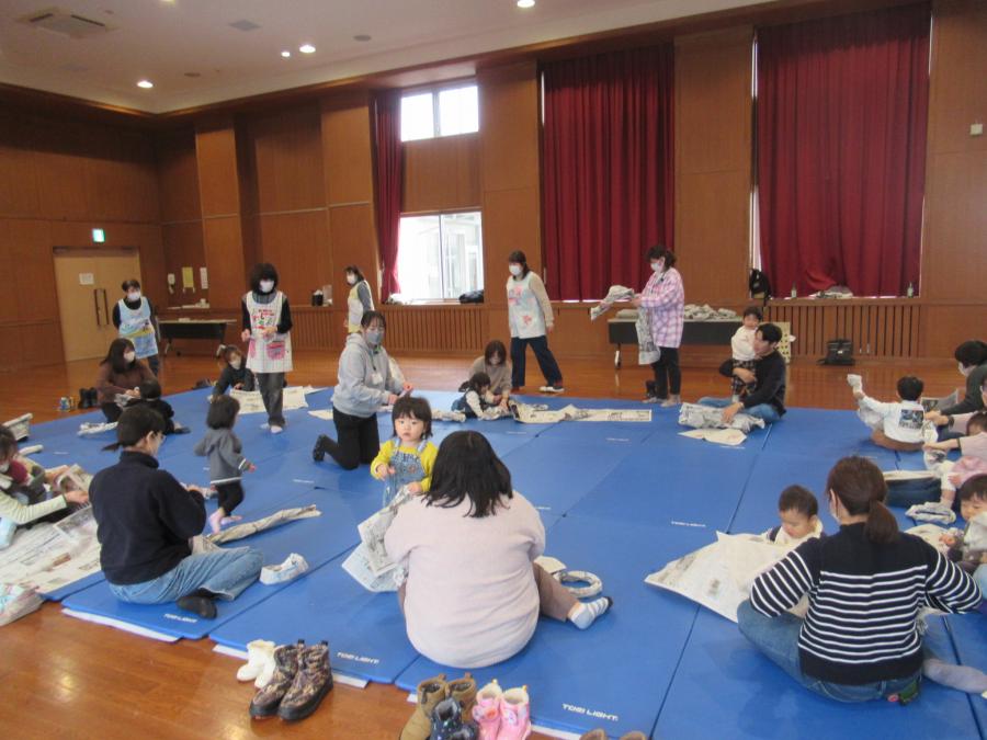 新聞紙を丸めて大きな輪を作っている親子の様子
