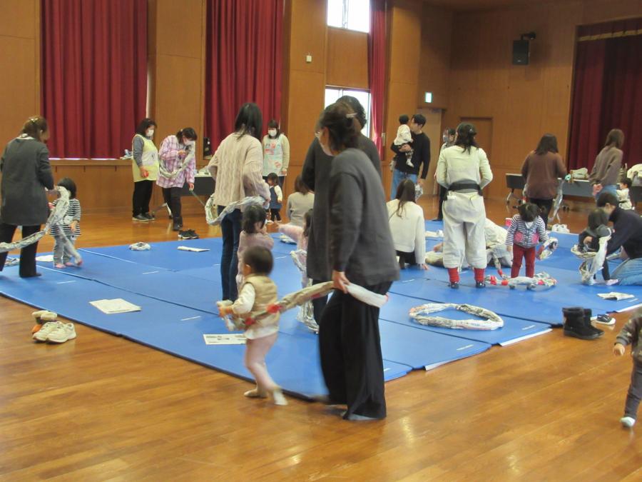 新聞紙の大きい輪で電車ごっこをしている親子の様子