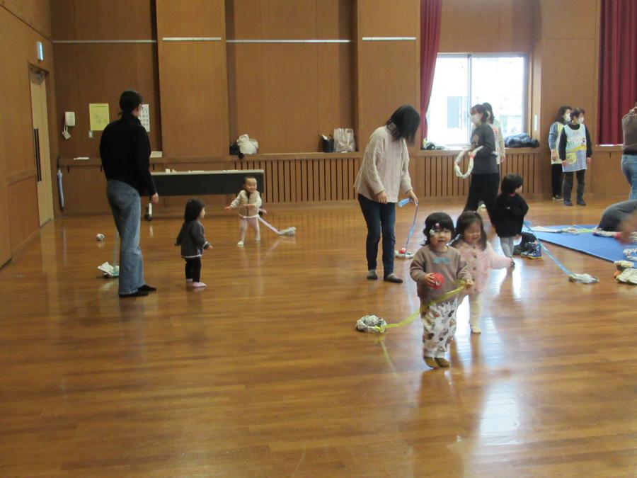 新聞紙の玉を乗せた新聞紙の小さい輪をひもを付けて引っ張って遊んでいる様子