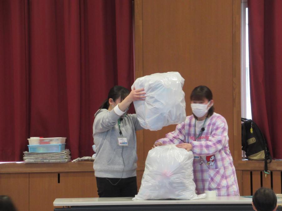 白い袋に片付けた新聞紙をいっぱいに入れて、2袋をつなげている様子
