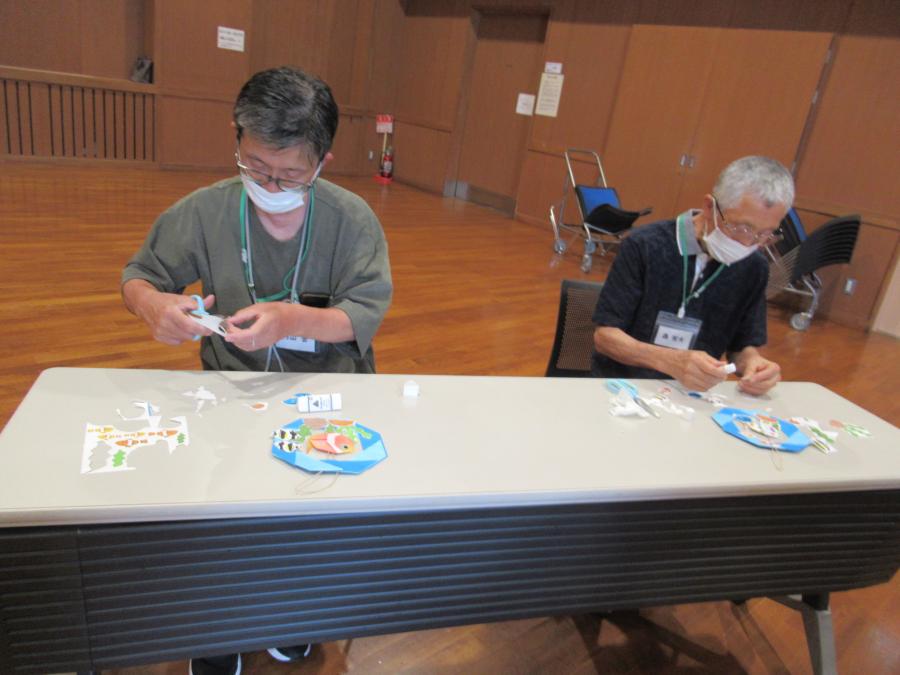 男性二人がイラストを切っている様子