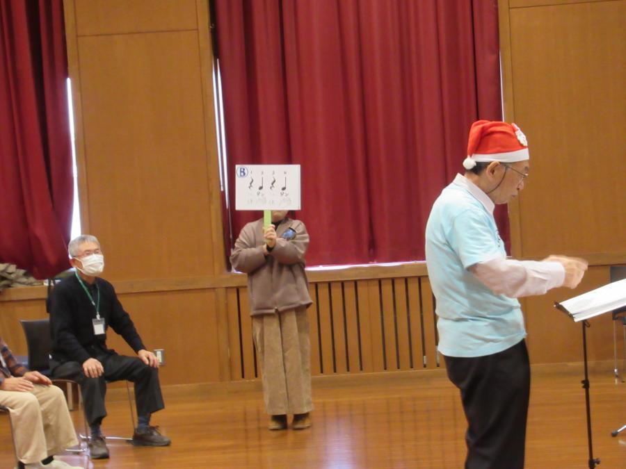 手を叩くリズムを書いたプラカードを持ち、それに合わせて手を叩く様子