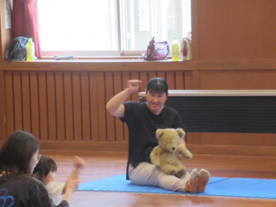 講師がぬいぐるみを膝に置いて、バスに乗っての遊びをしている所