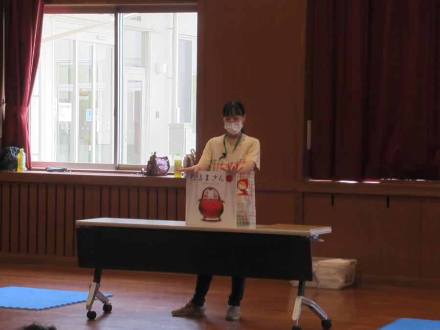 大型絵本の「だるまさんが」を読み聞かせする講師の写真