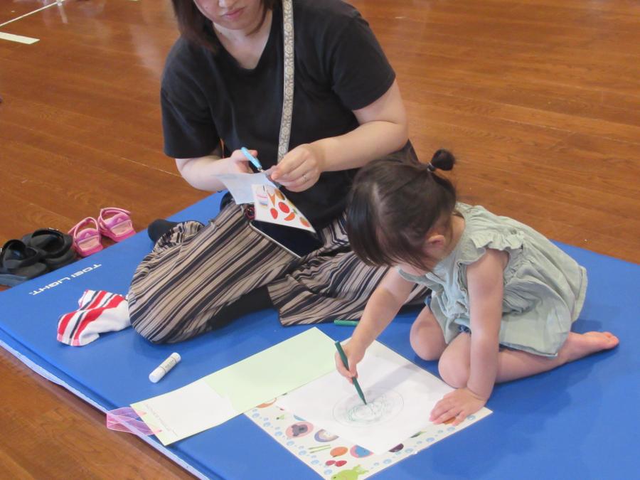 女の子が用紙に書いてある丸にぐるぐるとペンで書いているところ