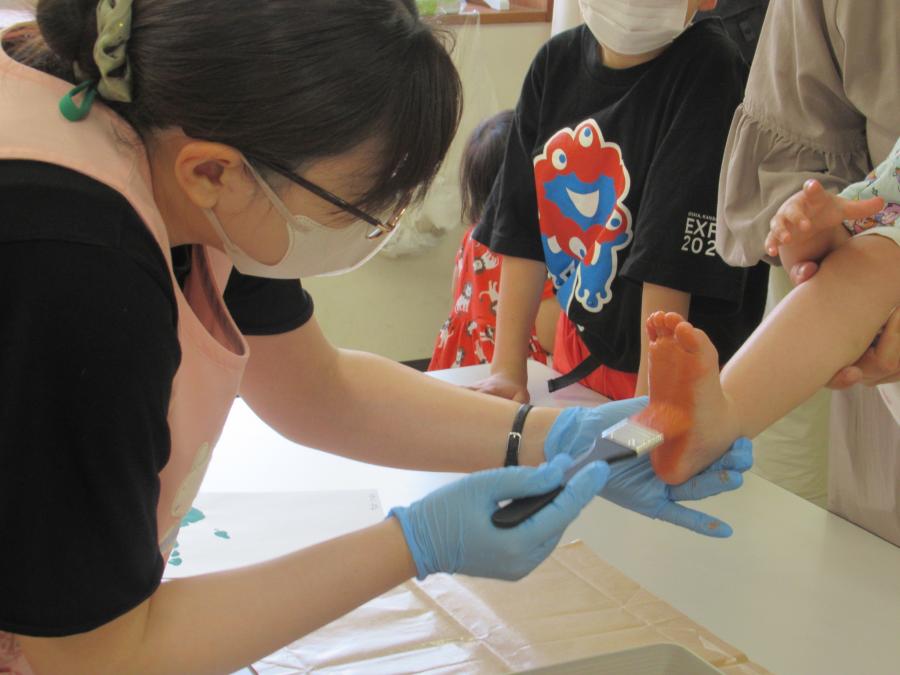 子どもの足に絵の具を塗っている様子