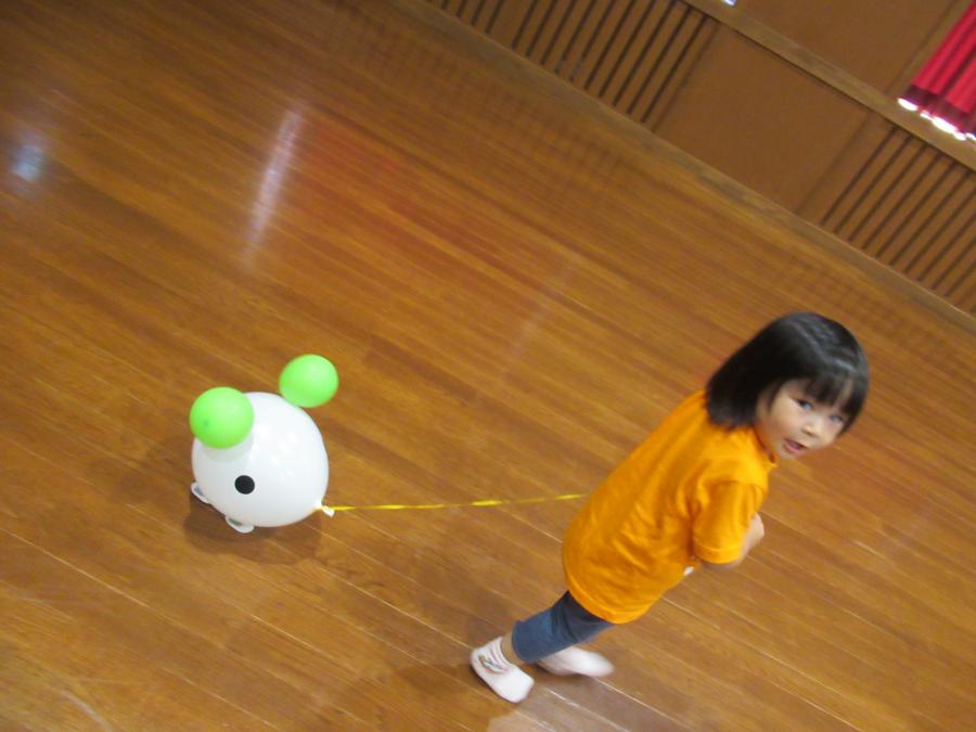 女の子が出来上がったバルーンの動物をひもを持って引っ張って遊ぶ様子