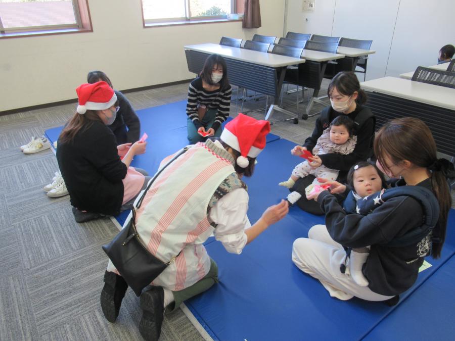 赤い折り紙でサンタを折る親子の様子