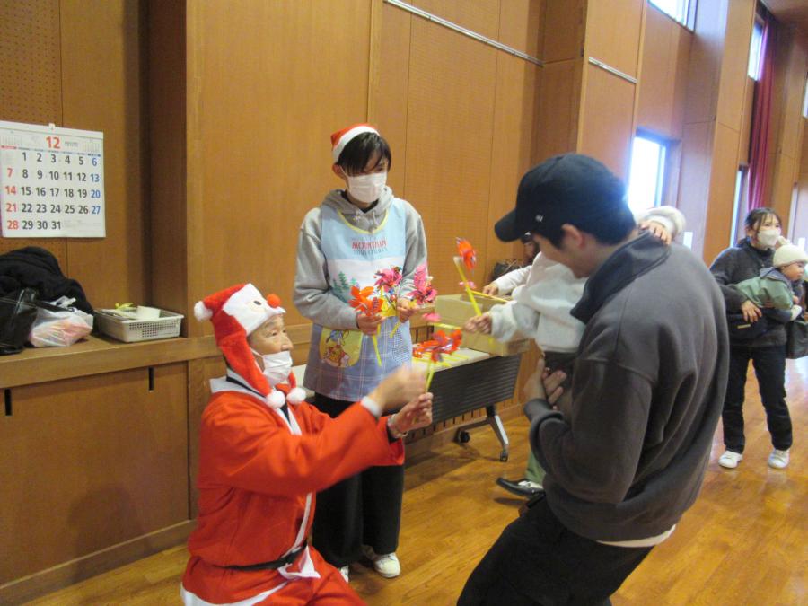 お父さんと子どもがサンタ館長から風車をもらう様子