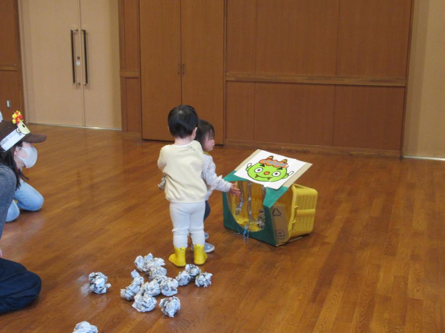 男の子が新聞の豆を箱の中に入れる遊びをしている所