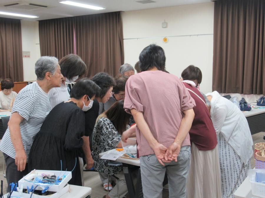 講師の回りに集まって編み方を見ている受講者の様子