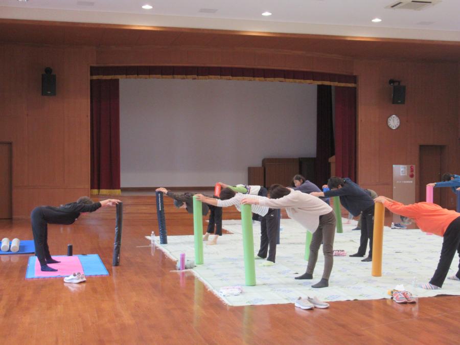 ポールを立てて手を伸ばし足の裏側を伸ばしている様子