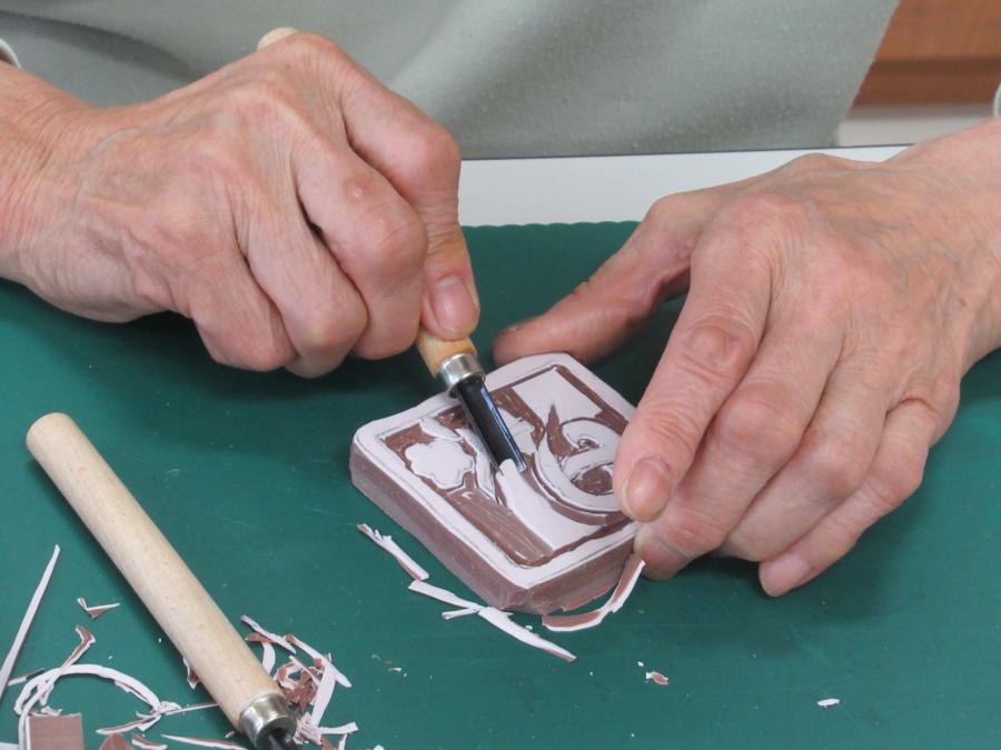 迎春の文字の消しゴムはんこを彫る手元の写真