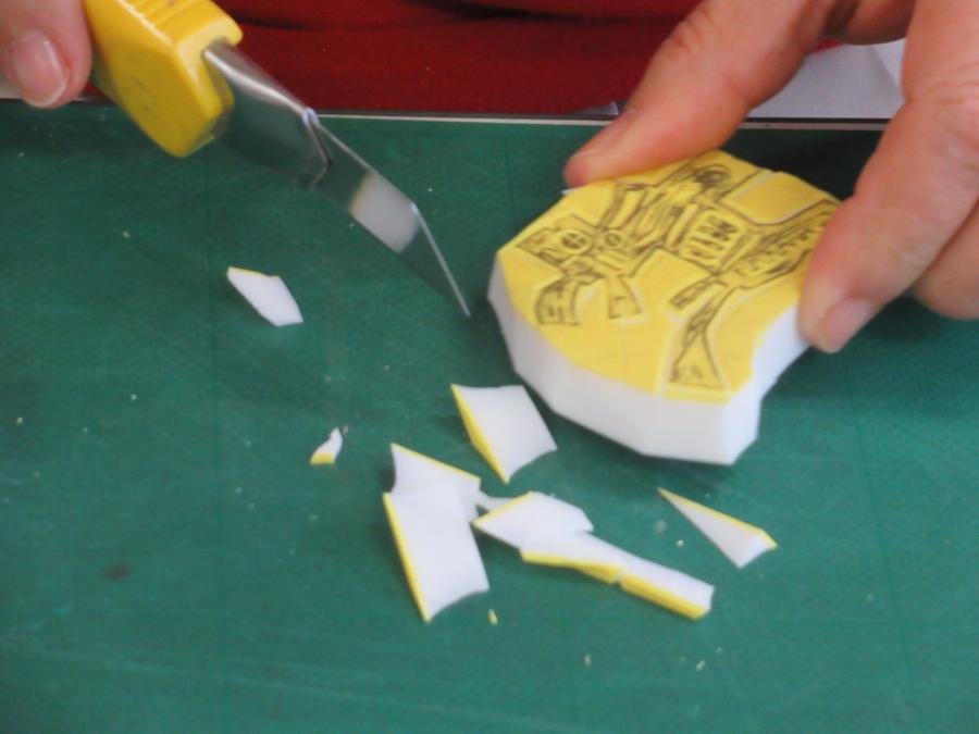 大きなカッターで消しゴムはんこのまわりを切る様子