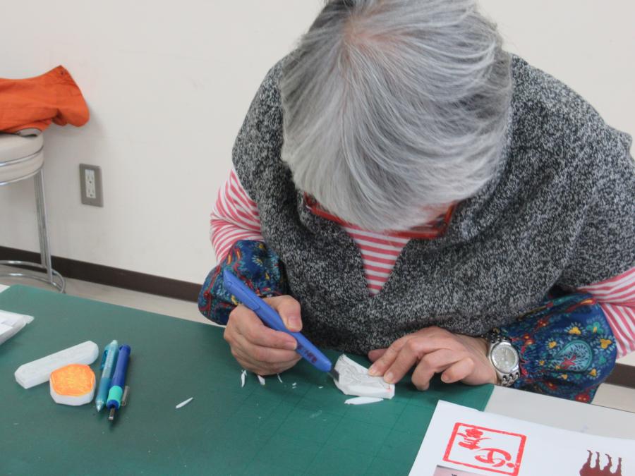 一人の女性が消しゴムはんこを彫っている様子