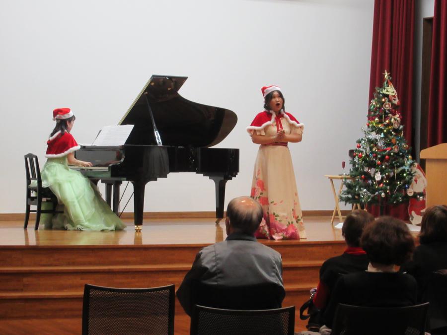 クリスマスの衣装で演奏し歌う様子