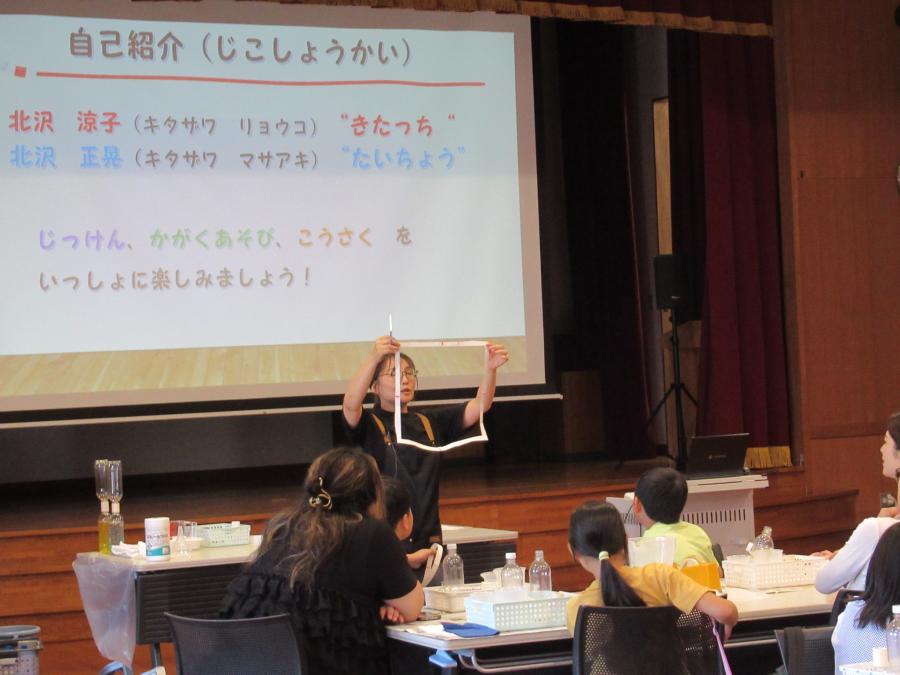 講師が四角に切れた紙を見せている様子