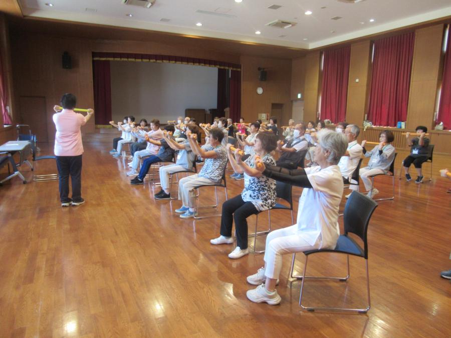 椅子に座って新聞棒を両手で前に出しているところ