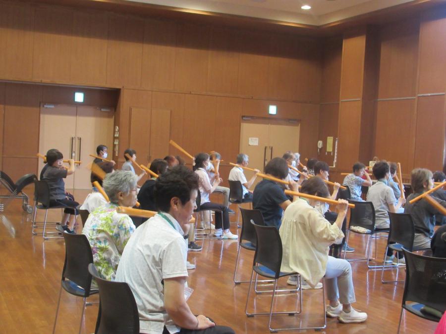 棒を使って肩たたきする様子