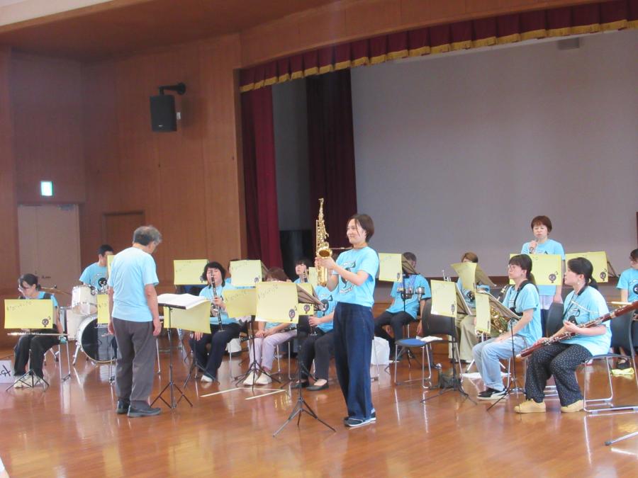アルトサックスの演奏者が楽器を上げて見せている様子