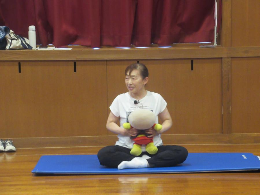 先生が見本にアンパンマンのぬいぐるみを抱いて、子どもの見本にしている様子
