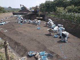 地面を削って遺構の痕跡を探す様子